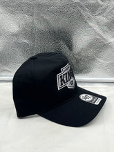 Load image into Gallery viewer, Los Angeles Kings NHL '47 Brand Black Hitch Adjustable Snapback Hat placed on a table, against a sports-themed background.