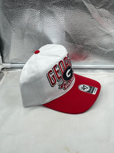 Load image into Gallery viewer, Person wearing the Georgia Bulldogs NCAA '47 Brand White Two Tone Hitch Adjustable Snapback Hat at a tailgate event, demonstrating fan spirit.
