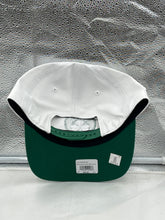 Load image into Gallery viewer, Boston Celtics NBA '47 Brand White Two Tone Hitch Adjustable Snapback Hat displayed on a wooden surface, emphasizing its stylish design.