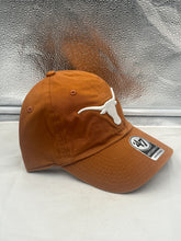 Load image into Gallery viewer, Texas Longhorns NCAA '47 Brand Orange Clean Up Adjustable Strapback Hat positioned next to other fan gear, emphasizing its must-have status for dedicated supporters.
