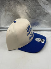 Load image into Gallery viewer, Lifestyle shot of a person wearing the Los Angeles Dodgers 1988 World Series MLB '47 Brand Natural Hitch Adjustable Hat while enjoying a sunny day, showcasing team spirit with this Los Angeles Dodgers hat.