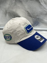 Load image into Gallery viewer, Close-up of the Vancouver Canucks NHL &#39;47 Brand Throwback Clean Up Tan Two Tone Adjustable Hat displaying the vintage logo and high-quality fabric.
