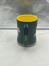 Load image into Gallery viewer, a green and yellow coffee cup sitting on top of a counter
