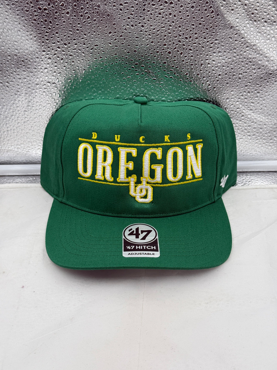 Oregon Ducks NCAA '47 Brand Green Hitch City Line Adjustable Snapback Hat displayed on a table, highlighting its vibrant green color and adjustable design, perfect for any Oregon Ducks hat fan.