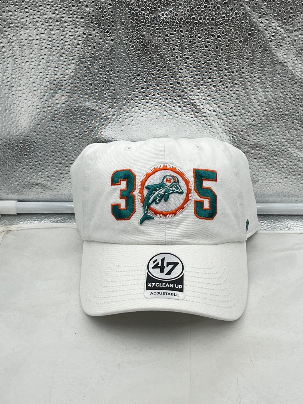 Miami Dolphins NFL '47 Throwback 305 White Clean Up Adjustable Strapback Hat displayed on a neutral background, showcasing the embroidered Dolphins logo and adjustable strap design.