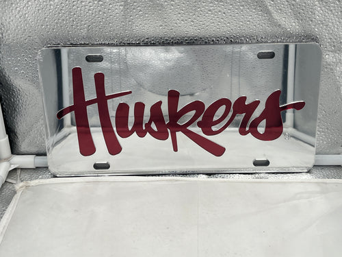Nebraska Cornhuskers NCAA Silver Mirrored Laser Cut License Plate by Craftique showcasing its vibrant reflective finish and detailed laser-cut logo, perfect for displaying team pride on your vehicle.
