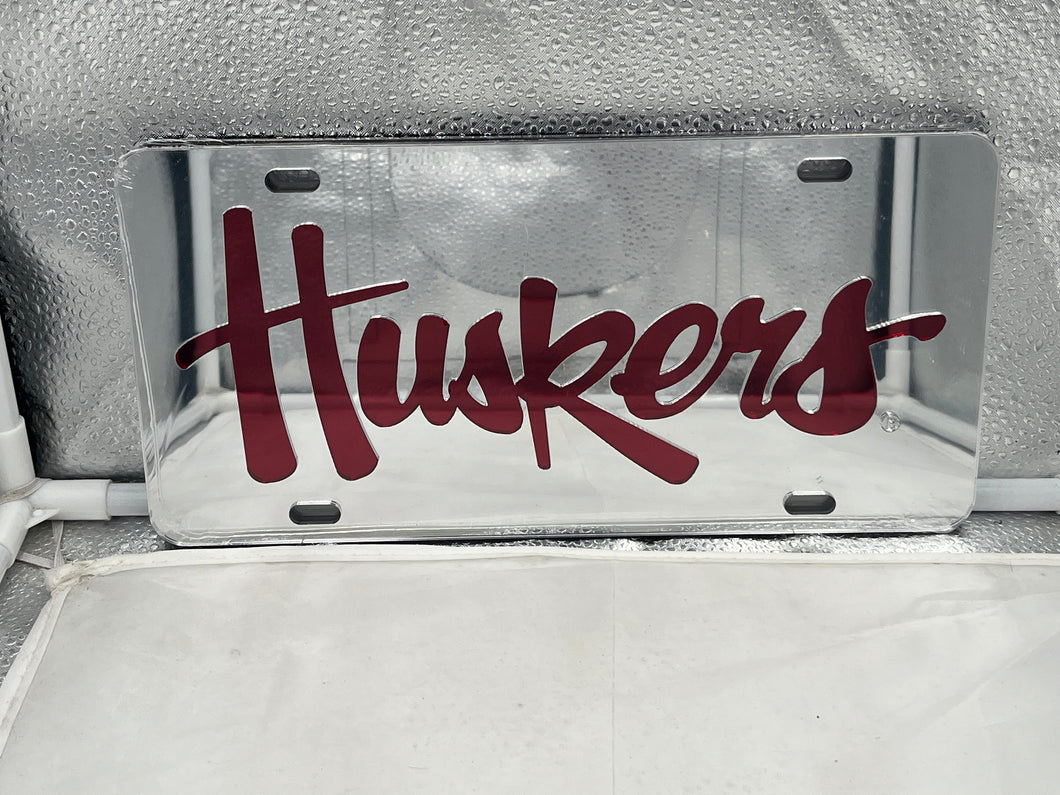 Nebraska Cornhuskers NCAA Silver Mirrored Laser Cut License Plate by Craftique showcasing its vibrant reflective finish and detailed laser-cut logo, perfect for displaying team pride on your vehicle.